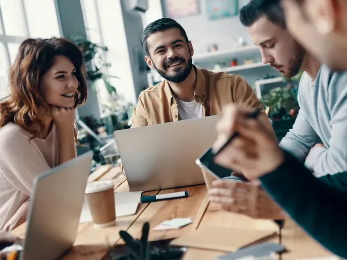 Group of young professionals discussing ideas and collaborating at a modern office table with laptops